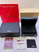 Open black Omega Speedmaster presentation box with red gift bag